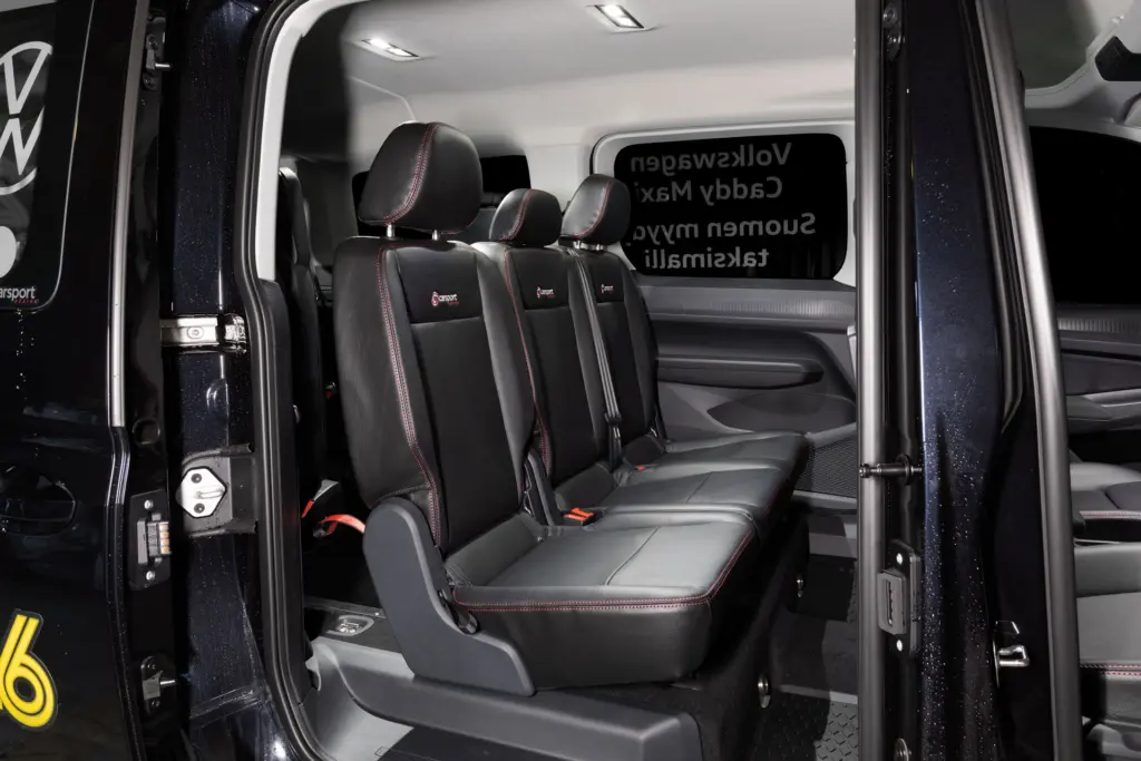 Volkswagen Caddy matkustamon istuimet mustalla nahkaverhoilulla, jossa punaiset koristetikkaukset.