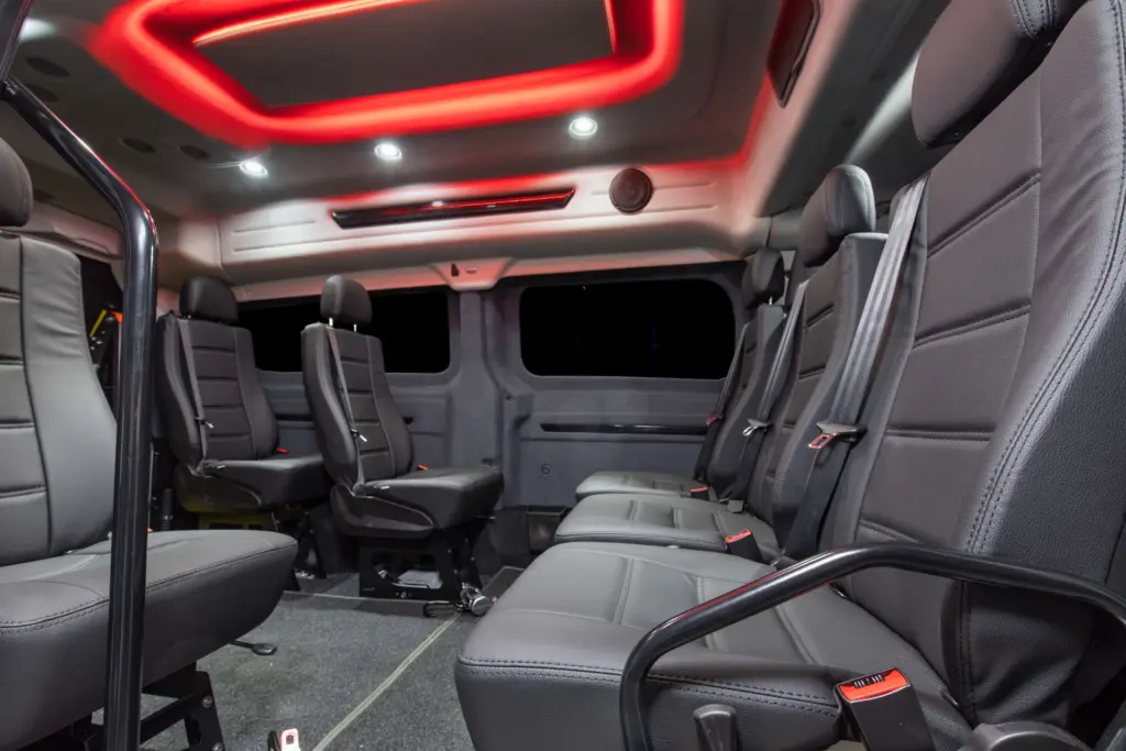 Näkymä liukuovelta Ford Customin sisään. Autossa punainen tunnelmavalaistus vaaleassa katossa, mustat seinät ja mustat nahkaistuimet.
